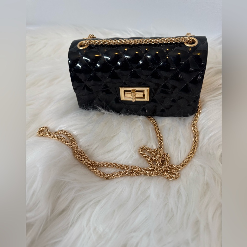Black plastic shell small shoulder bag with gold clasp, and shoulder chain